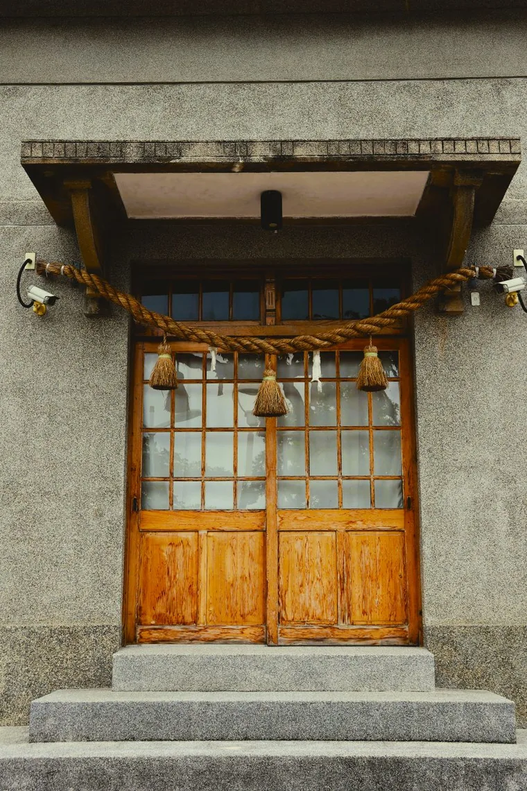 A straw shimenawa rope with white paper shide above a wooden door